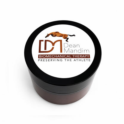 A round black plastic jar with a white lid label featuring the logo and name 'Dean Mandim' and the text 'BIOMECHANICAL THERAPY' and 'PRESERVING THE ATHLETE'.